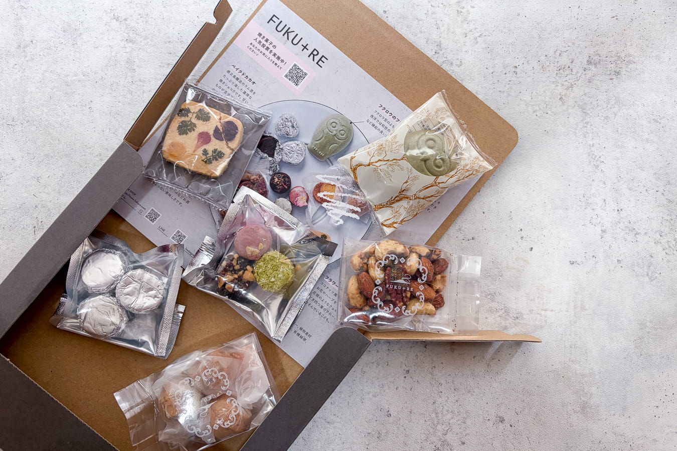 FUKU+REの【ポスト投函】焼き菓子試食セットの商品画像。ポスト投函可能な薄型パッケージに、フクロウのフロランタンや個包装の焼き菓子を少量ずつ詰め合わせた自分用の下見セット