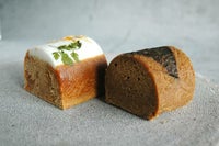 鹿児島ふくれ菓子ミニ2種セット（Duo A）。黒糖色の「サンボ」と食用花が飾り付けられた白色の「コミカン」が隣り合い、蒸し生地の質感と色の対比が鮮やかな手土産向けスイーツ。