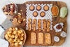 芋飴燻製ナッツ、鰹節ポップコーン、酒粕レーズンビスコッティ、焼き菓子などが木製のプレートに美しく並べられた父の日限定詰め合わせギフト