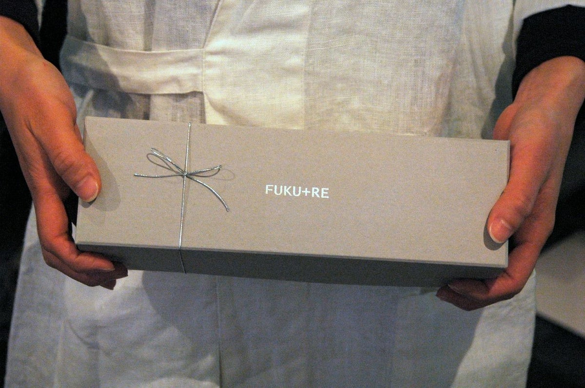FUKU+REロゴ入りギフト箱を手に持つ様子。お礼やお返しに喜ばれる上品なお菓子ギフト。
