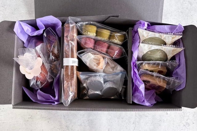 焼き菓子の詰め合わせ。クッキー、フロランタン、フクロウ型の焼き菓子、丸い菓子などがシンプルで上品なギフトボックスの中にセッティングしたものを上から撮影されている。