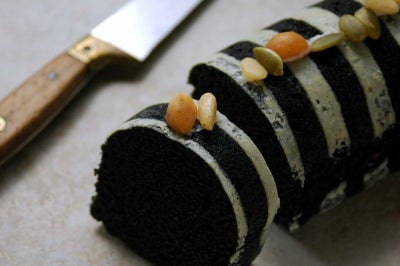 黒ねりごまをたっぷり使用したスイーツ。美しいストライプ模様のふくれ菓子がカットされ、ナッツがトッピングされている