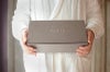 FUKU+RE(フクレ)の店員が、FUKU+REと刻印された上品なグレーのギフトボックスを両手で丁寧に持っている様子。贈り物としての丁寧さや温かみが伝わるシーン