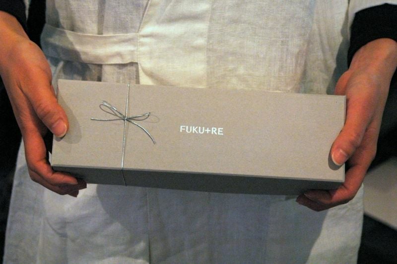 FUKU+REロゴ入りギフト箱を手に持つ様子。お礼やお返しに喜ばれる上品なお菓子ギフトボックス。